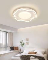 Cloud shaped ceiling lamp lit above a bed with a plant and framed pictures on the wall