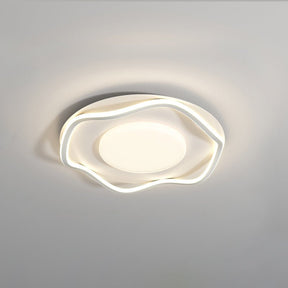 White cloud shaped ceiling lamp lit at an angle against a plain pale wall