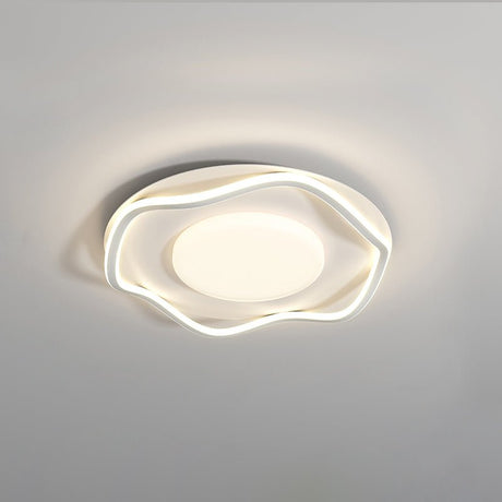 White cloud shaped ceiling lamp lit at an angle against a plain pale wall