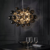 The cluster lit above a dark round table with wine glasses and a glass bowl