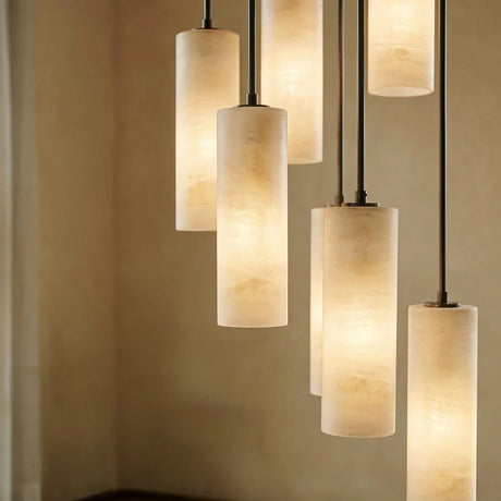 Four lit alabaster cylinders at different heights on black cords