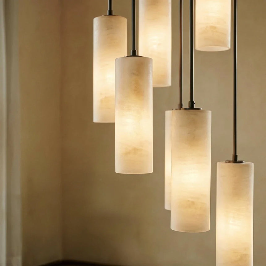 Four lit alabaster cylinders at different heights on black cords