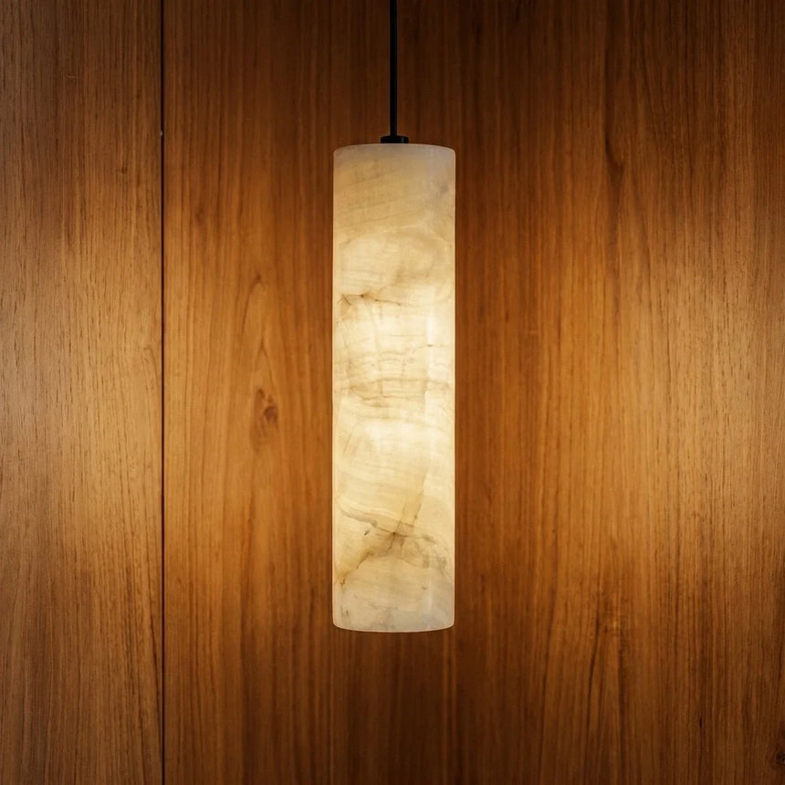 A lit alabaster cylinder hung against a warm timber wall panel