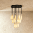 A wide cluster of alabaster cylinders lit, on black cords from a round plate