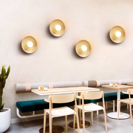 Four sconces lit along a wall above a banquette with tables and chairs