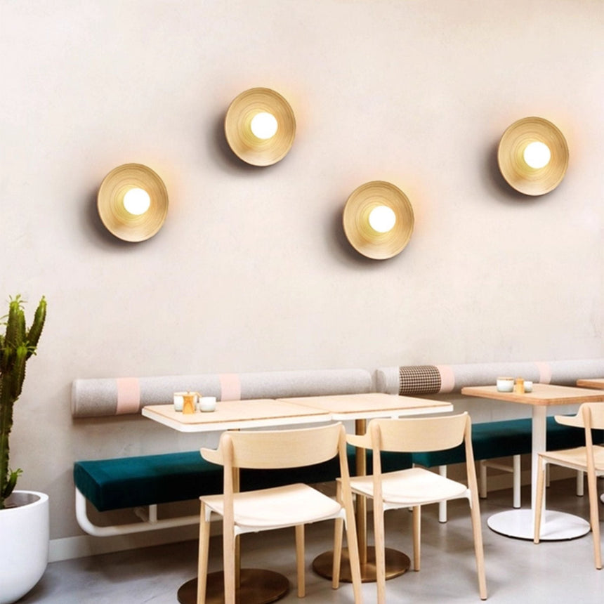 Four sconces lit along a wall above a banquette with tables and chairs