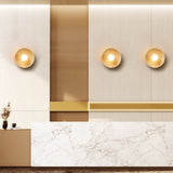 Three sconces lit on a slatted wall above a marble fronted counter