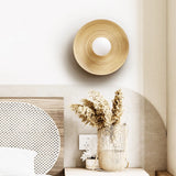 Sconce lit beside an arched headboard above dried flowers in a ribbed vase
