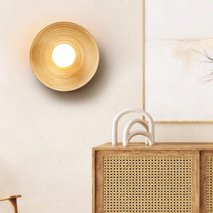 Sconce lit above a cane fronted sideboard beside a framed print and a bag