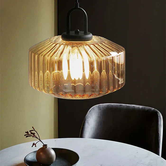 Amber ribbed drum above a round table with a dark chair and a small bowl