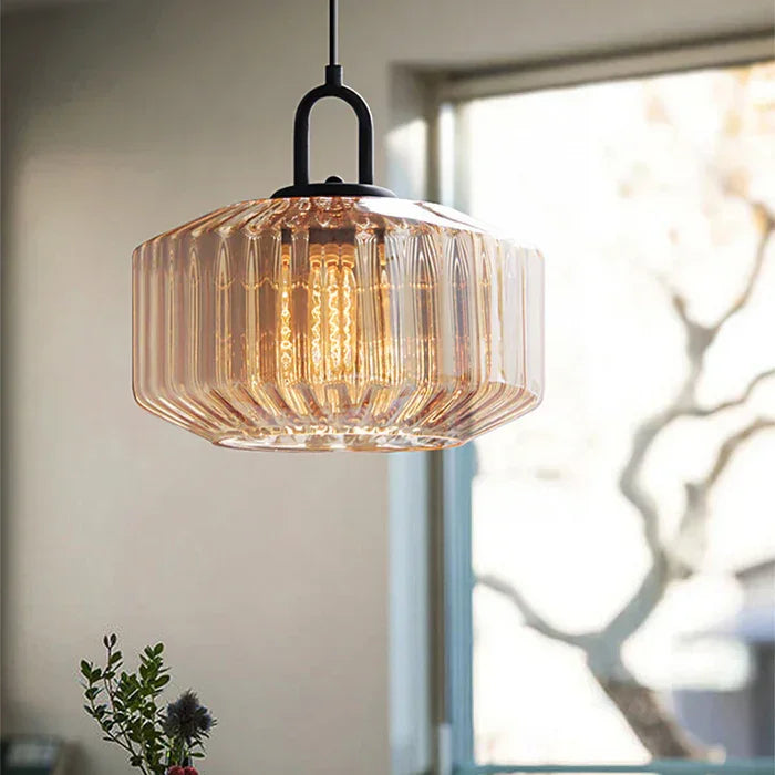 Amber ribbed drum lit against a bright window with bare branches outside