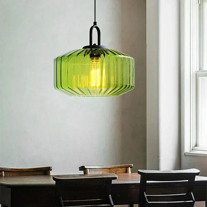 Green ribbed drum above a cafe table with dark chairs and a pale wall