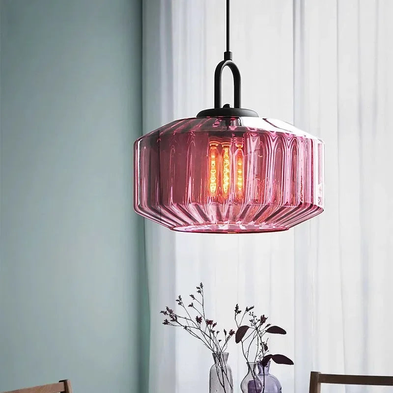Purple ribbed drum lit beside a sheer curtain and a vase of dried stems