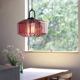 Purple ribbed drum shade hanging by a window above a wooden dining table