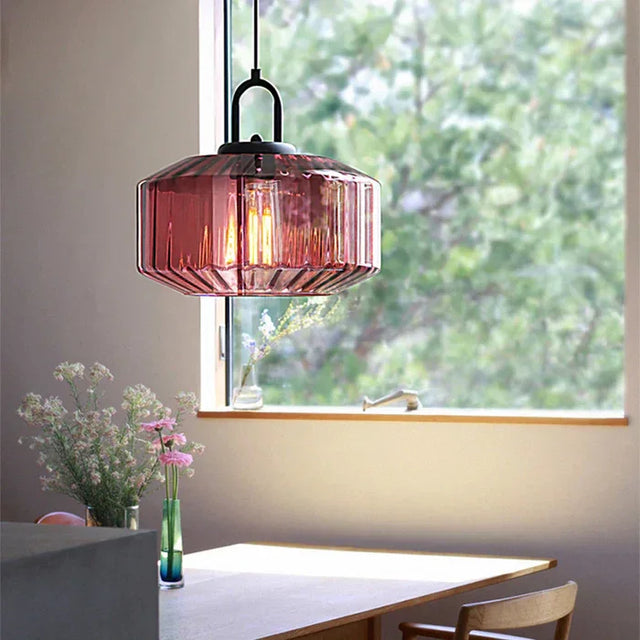 Purple ribbed drum shade hanging by a window above a wooden dining table