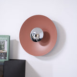 The orange disc with a chrome center above a black cabinet with a book