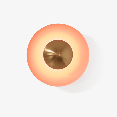 Round orange disc wall light with a copper tone center that glows around its edge