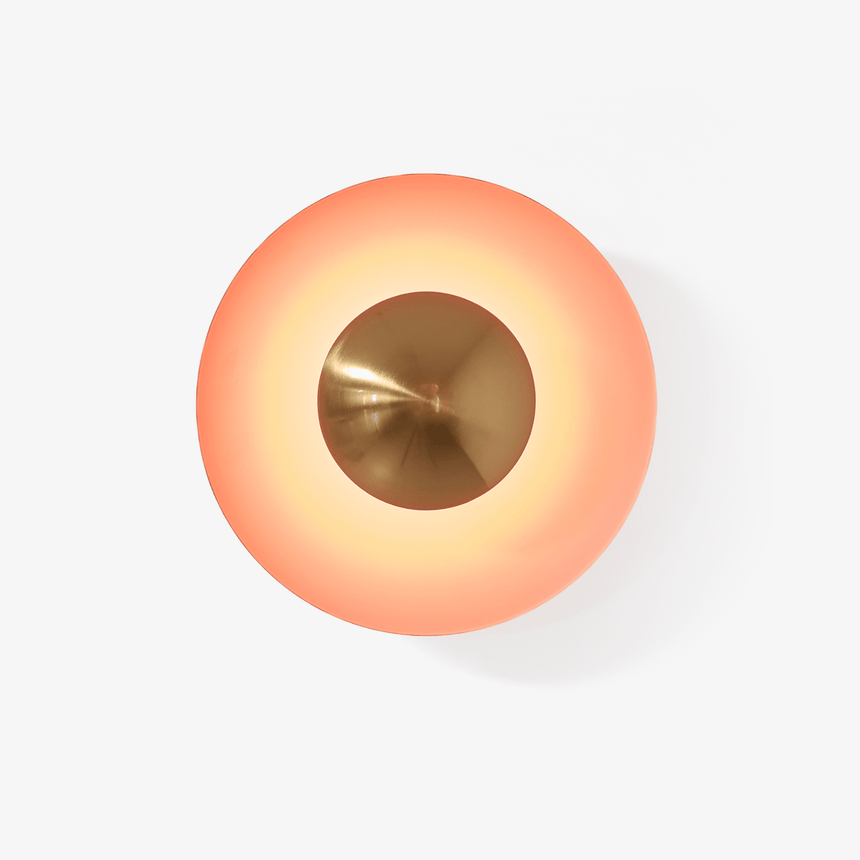 Round orange disc wall light with a copper tone center that glows around its edge