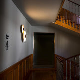 Two disc lights lit in a stairwell beside wood paneling