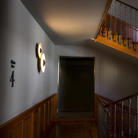 Two disc lights lit in a stairwell beside wood paneling