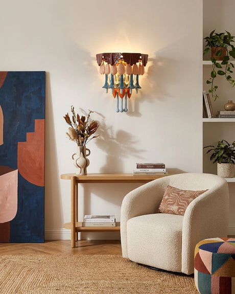 The sconce above a wood console beside a round armchair and a patterned pouf