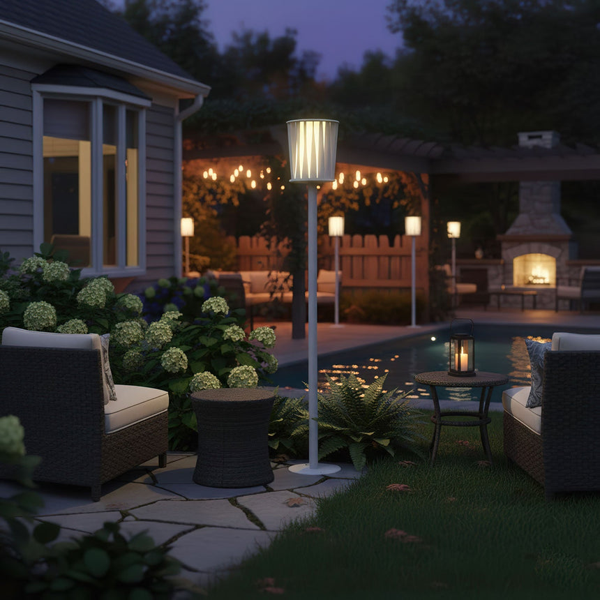 The lamp lit on a lawn beside hydrangeas with a lit house behind