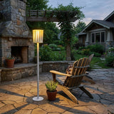 The lamp lit on a stone terrace beside a timber chair and a pot
