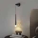 The black cone lit above a round nightstand with two vases beside a headboard