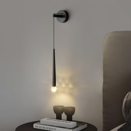 The black cone lit above a round nightstand with two vases beside a headboard