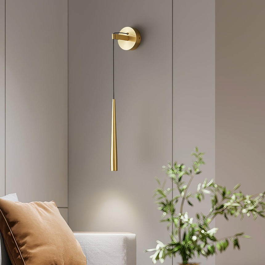 The brass cone lit above a sofa cushion and a green plant