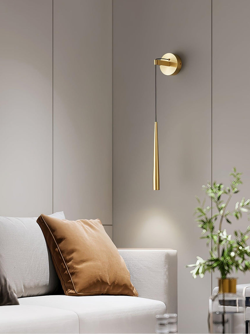 The brass cone lit above a white sofa with a cushion and a plant