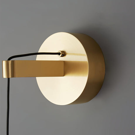 Close view of the round brass wall plate and the cable holder