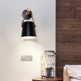 Sconce lit above a bed beside a wire basket lamp on a bedside table