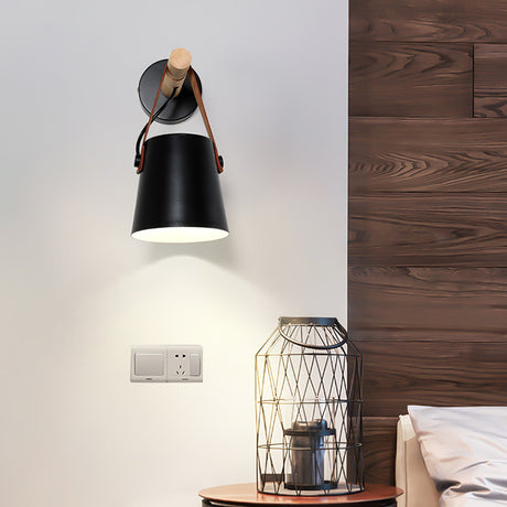 Sconce lit above a bed beside a wire basket lamp on a bedside table