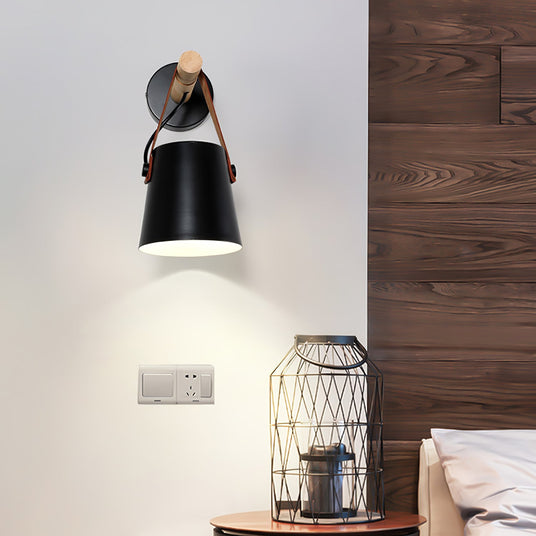 Sconce lit above a bed beside a wire basket lamp on a bedside table