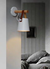White cone lit beside a bed with a gray headboard and folded bedding