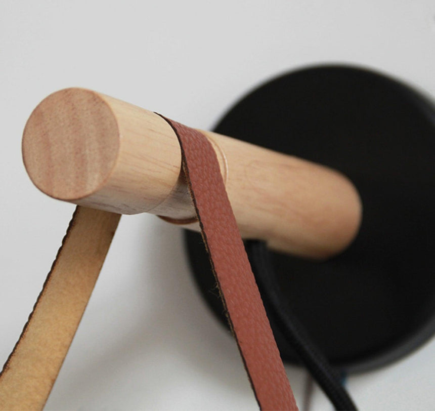 Close view of the leather strap wrapped over the wood bar and stud
