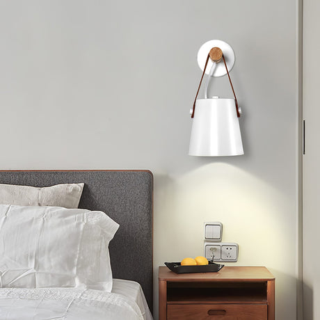 White cone lit above a wood nightstand beside a bed with white pillows
