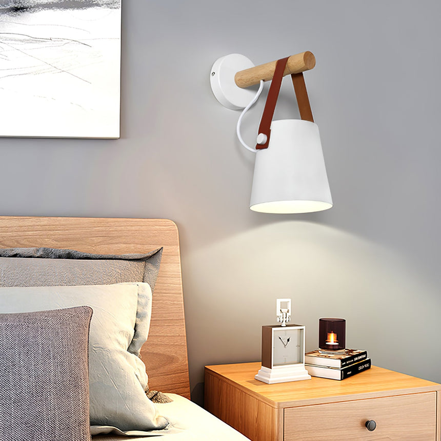 Sconce lit above a nightstand with stacked books and a framed photo