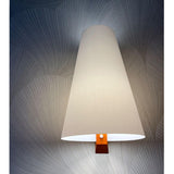 The cone lit warm on a dark textured wall, light spilling from the base