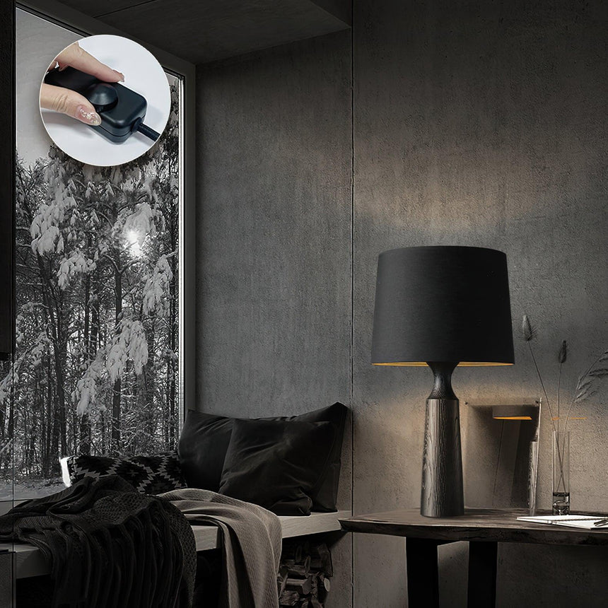 Console table lamp in black on a table beside a draped chair