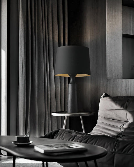 Console table lamp in black lit on a round table by a sofa