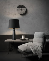 Console table lamp in black lit on a console below a wall clock