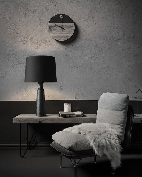 Console table lamp in black lit on a console below a wall clock
