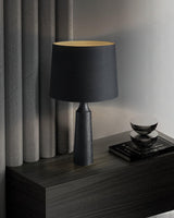 Console table lamp in black on a dark console beside a curtain