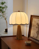 Scalloped shade lamp lit on a wood desk beside a framed picture
