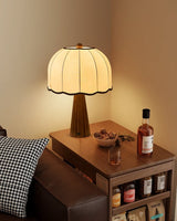 Scalloped shade lamp lit on a side table beside a bottle and a tray