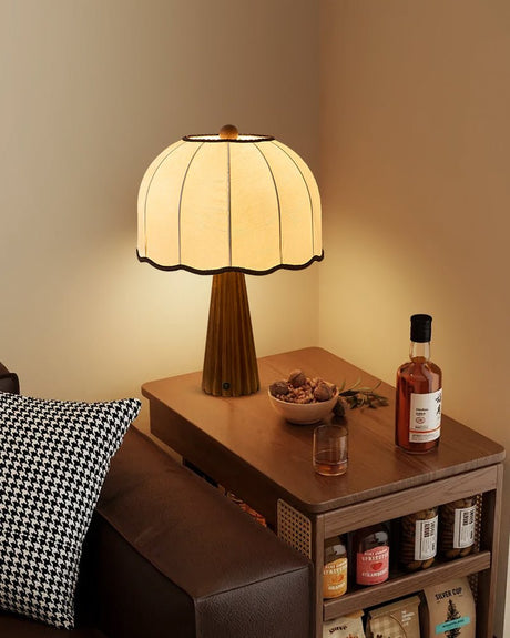 Scalloped shade lamp lit on a side table beside a bottle and a tray