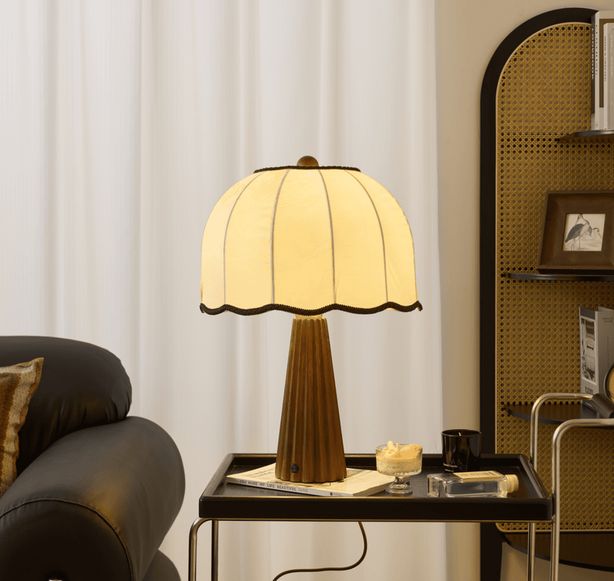 Scalloped shade lamp lit on a black tray table beside a leather sofa