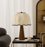 Scalloped shade lamp unlit on a tray table beside a leather sofa